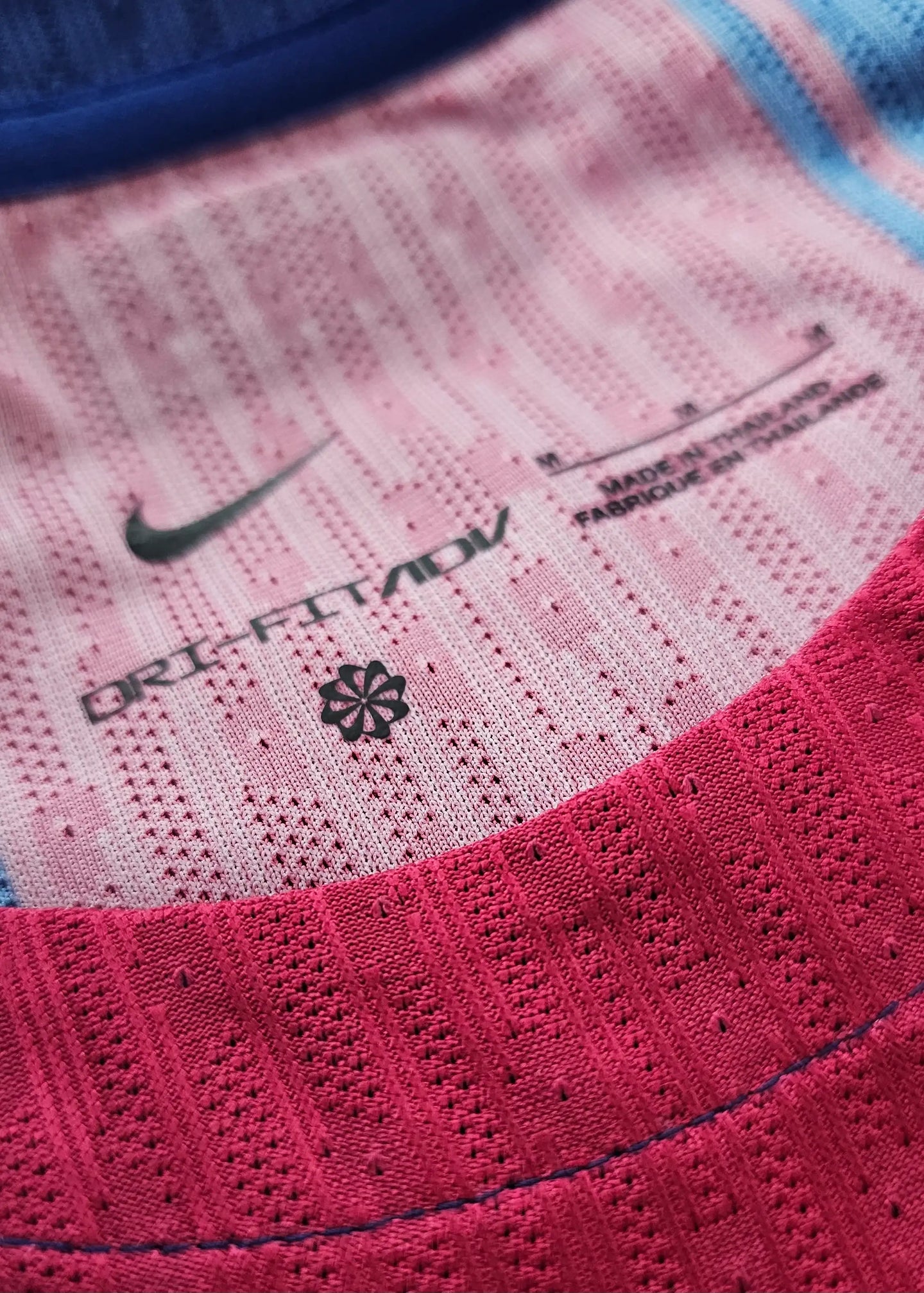 Detail view showing the Nike logo, DRIFT FIT ADV text, and size M label in pink and blue.