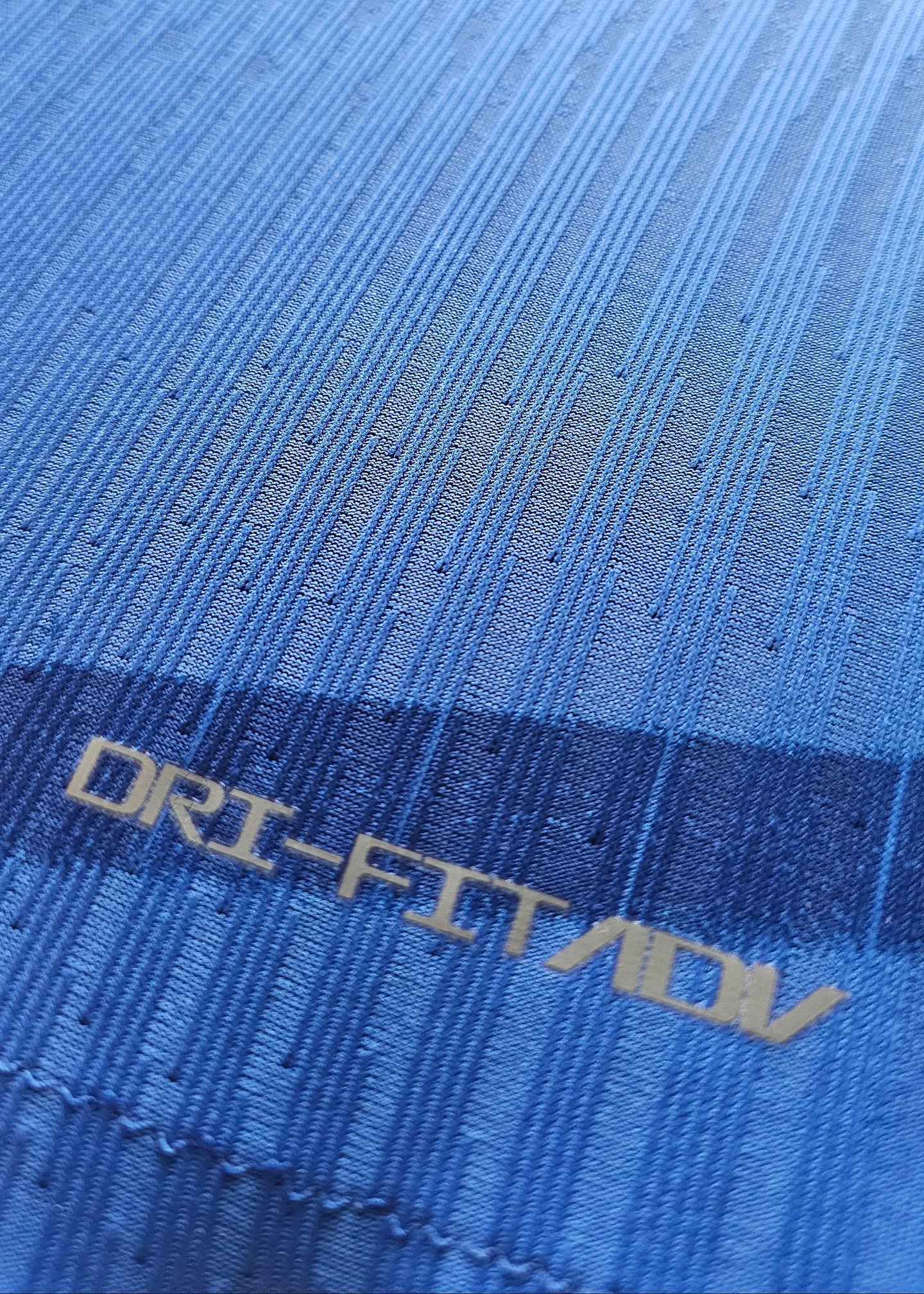 Close-up of the fabric texture with DRI-FIT ADV text on Chelsea blue shirt.