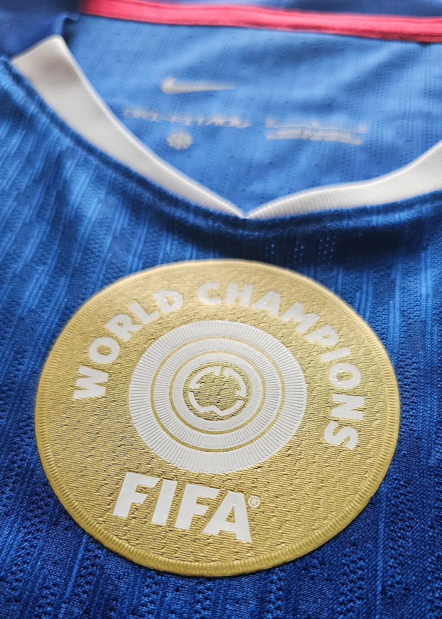 Close-up view of the FIFA World Champions badge in gold on a blue football shirt.