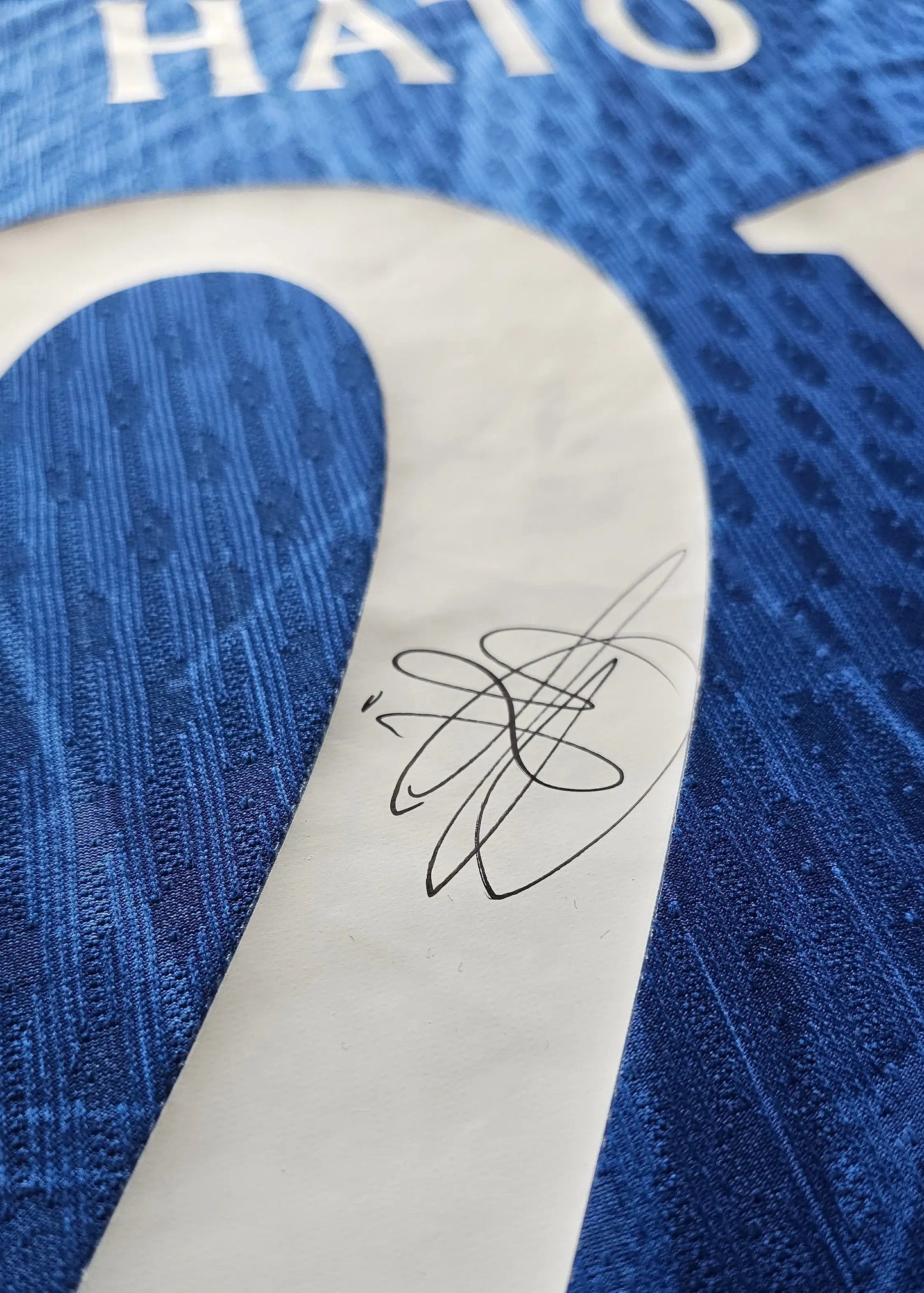 Close-up of Jorrel Hato's signature on the No. 21 Chelsea football shirt.