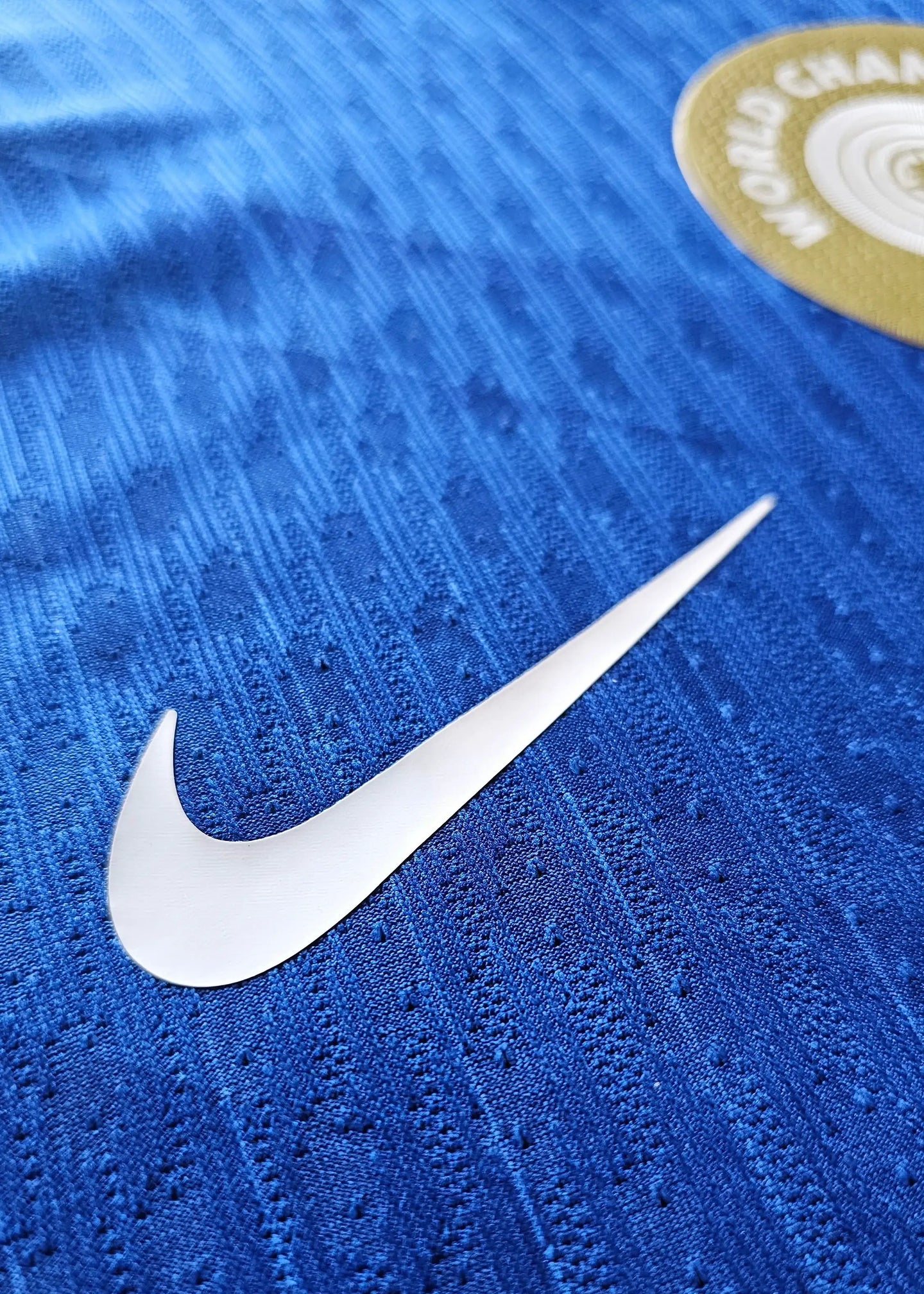 Close-up showing the white Nike logo on a blue football shirt with textured fabric.