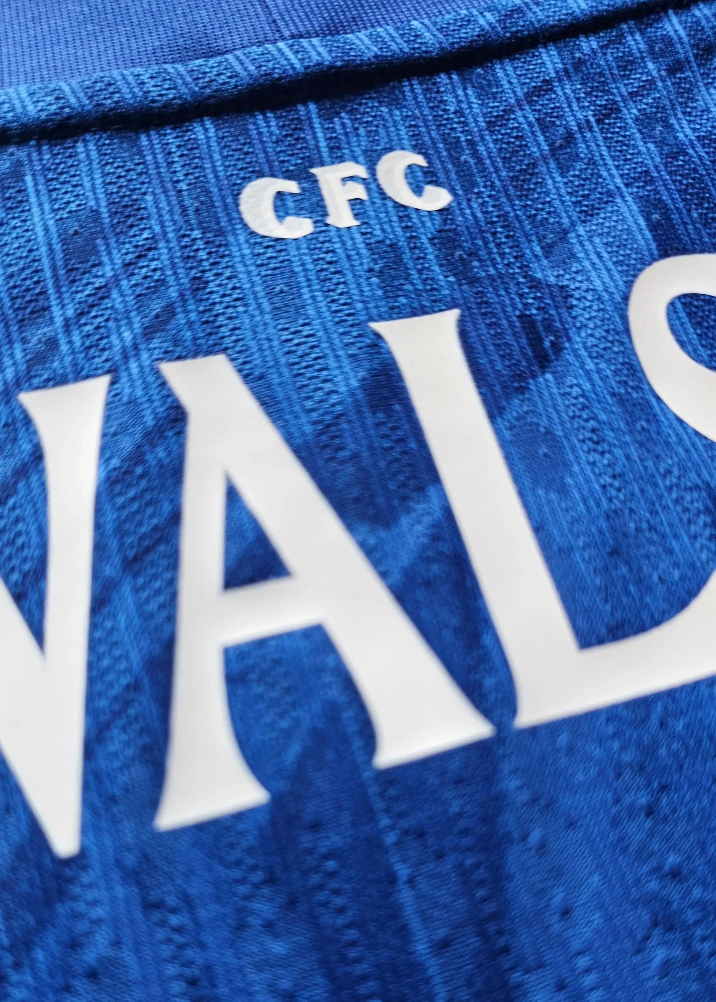 Detail view showing the name Walsh and CFC embroidered on a blue football shirt.