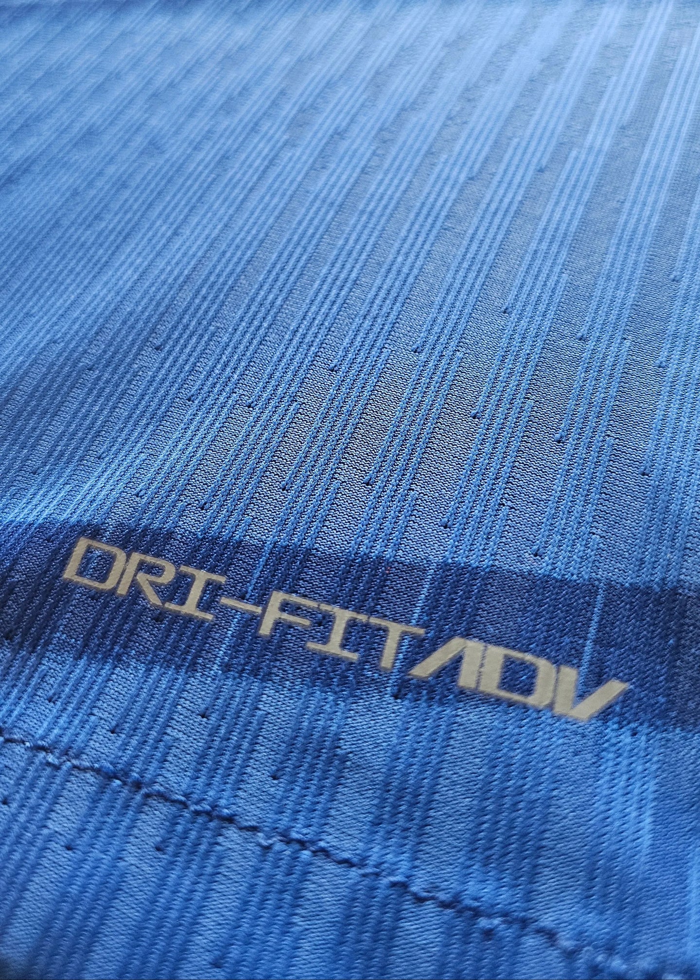 Close-up of blue fabric showing DRI-FIT label with pattern details.