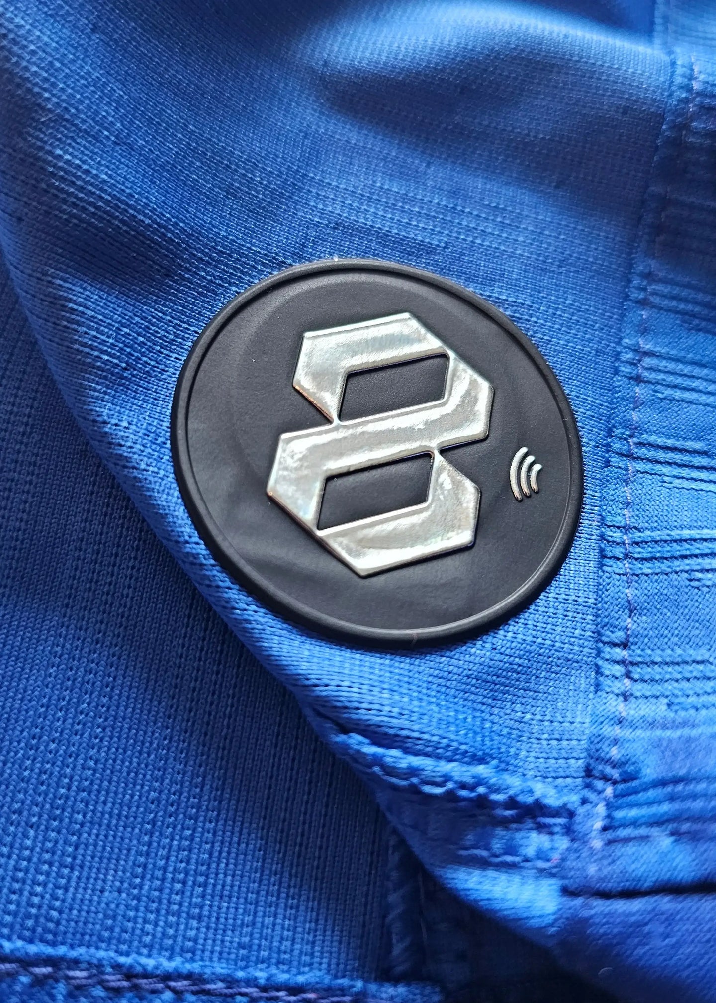 Close-up detail of blue fabric with black round badge featuring the number 8.