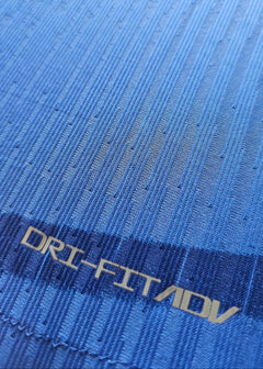 Close-up of blue fabric with 'DRI-FIT ADV' text visible on the football shirt.