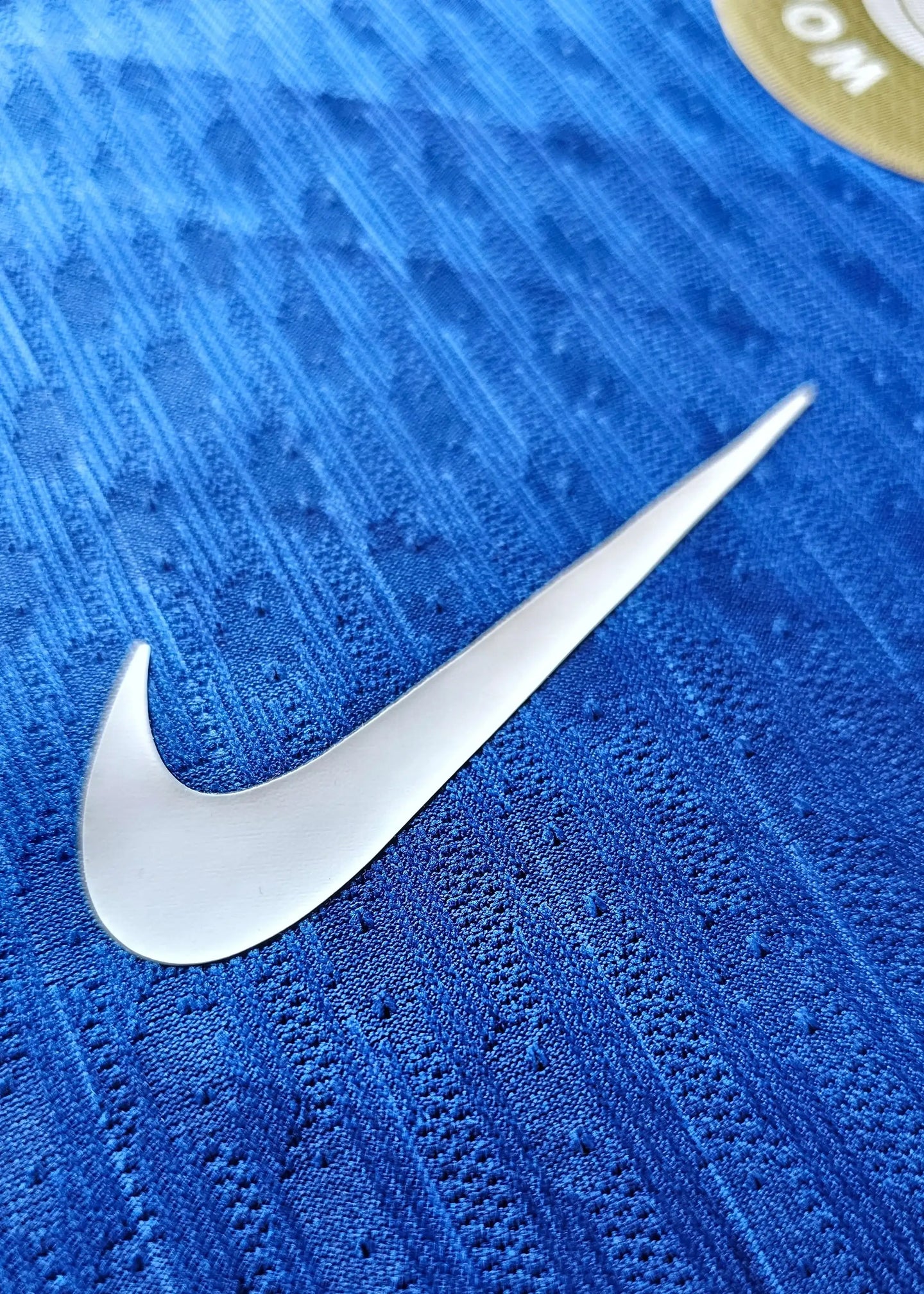 Close-up view of Nike logo on blue fabric texture of Chelsea signed shirt.