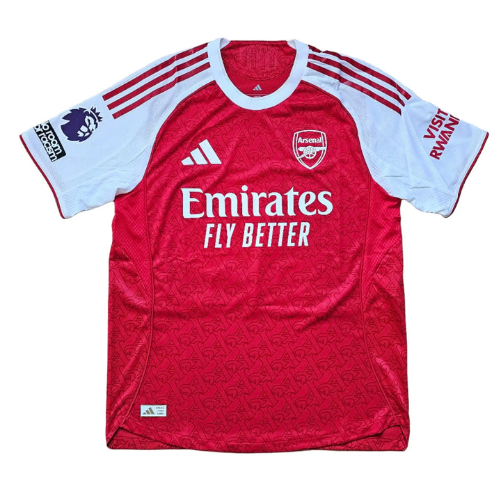 Front view featuring Arsenal crest, Emirates sponsor, and red body with white sleeves.