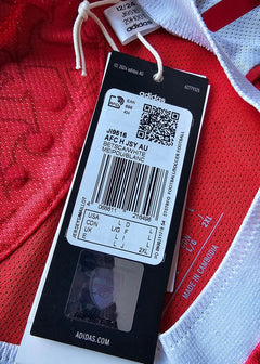Label showing size and barcode on a red football shirt with white trim, featuring an adidas tag.