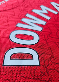 Close-up of the name Dowman and No. 56 on a red football shirt with a textured background.
