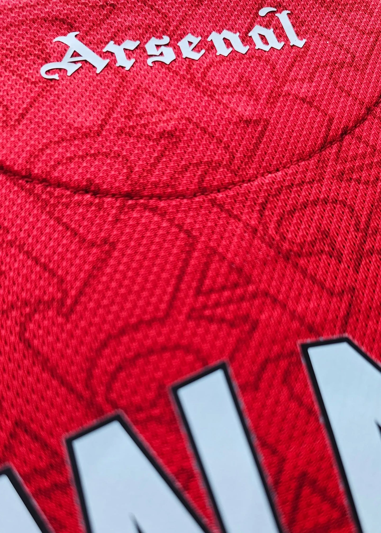 Close-up of the Arsenal crest with intricate detailing on a red football shirt.