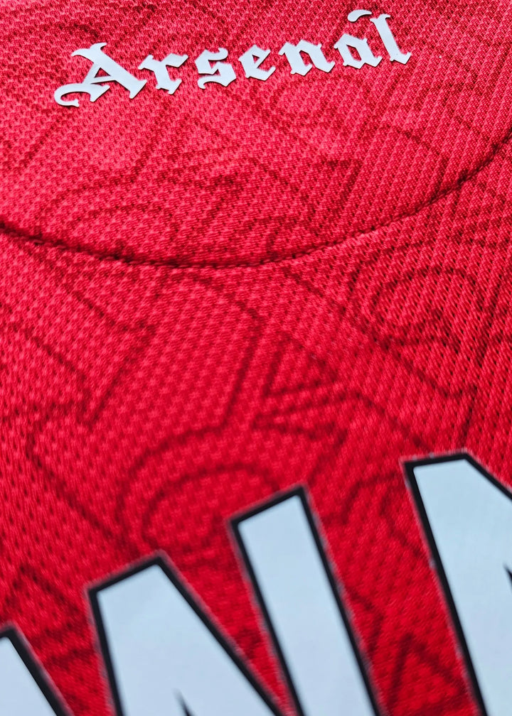 Close-up of the Arsenal crest with intricate detailing on a red football shirt.