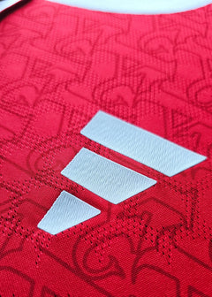 Close-up of the white adidas wordmark on a textured red background with subtle pattern.