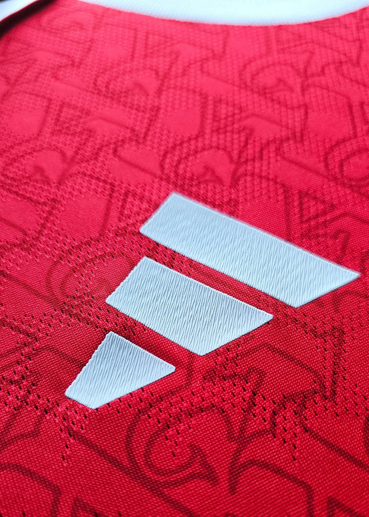 Close-up of the white adidas wordmark on a textured red background with subtle pattern.