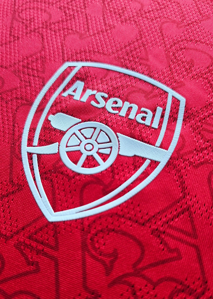 Back view showing the Arsenal crest in white with a red background pattern.
