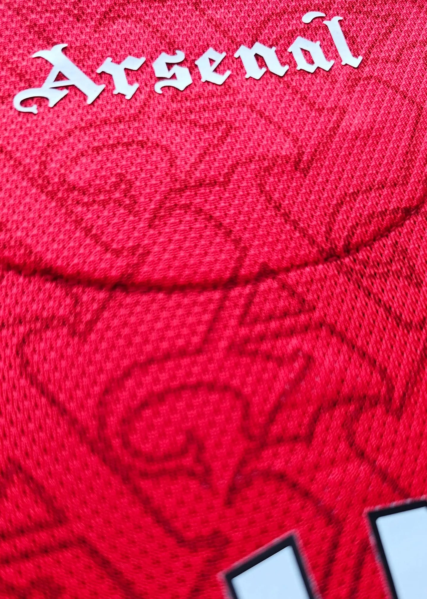 Back view highlighting 'Arsenal' in white lettering against a textured red background.