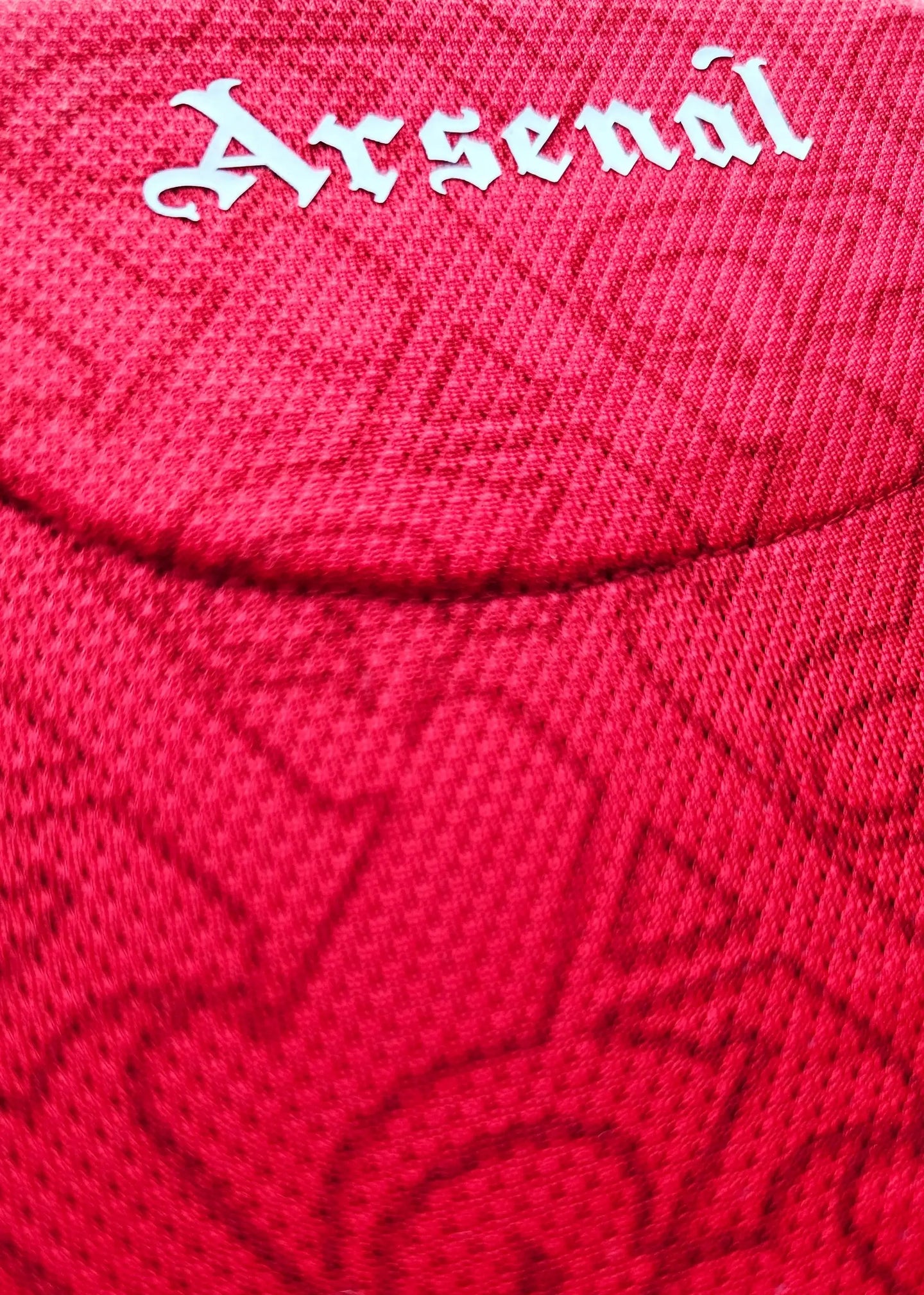 Close-up of the Arsenal crest in white on a red football shirt.