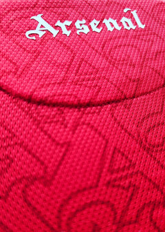 Close-up of the Arsenal crest in white on a red football shirt.