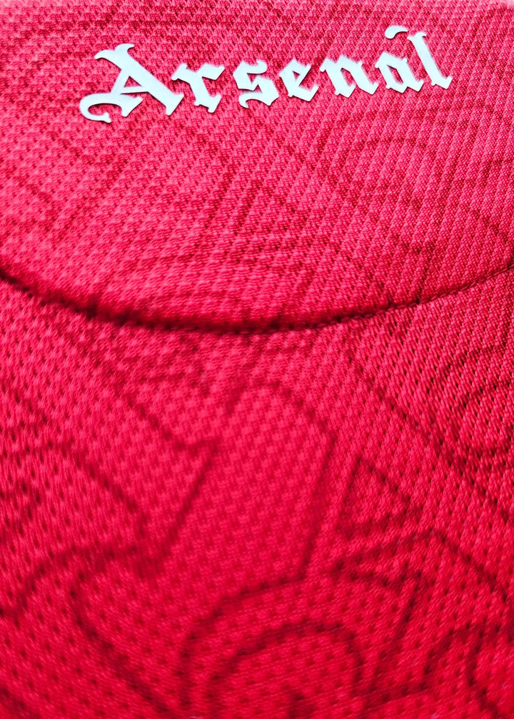 Close-up of the Arsenal crest in white on a red football shirt.