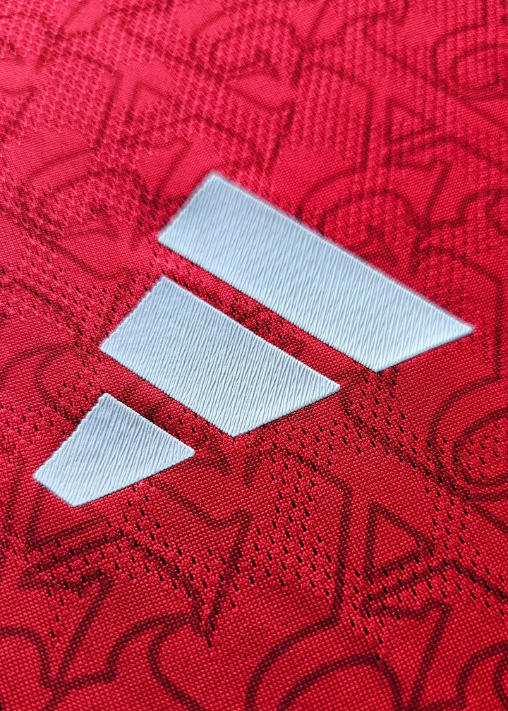Close-up view of the Adidas logo in white on red fabric with pattern.