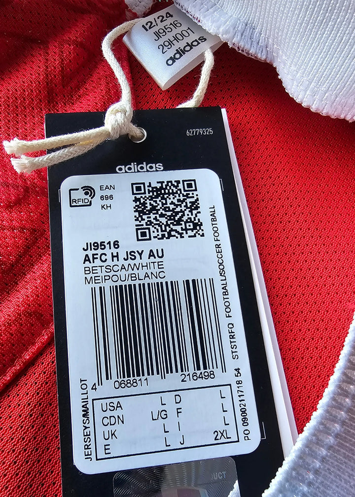 Detailed view of care tag showing adidas label and size information on a red football shirt.
