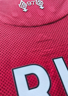 Detail showing the embroidered 97 flames symbol on a red Liverpool football shirt.