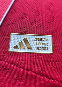 Close-up of the adidas label stating AUTHENTIC LICENSED PRODUCT on a red football shirt.