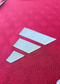 Close-up of the embroidered three stripes logo on the red football shirt.