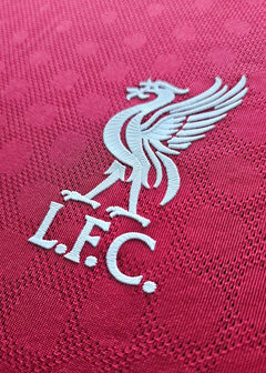 Crest detail of Liverpool F.C. featuring a white embroidered liver bird and 'L.F.C.' text.