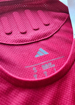 Close-up of adidas label showing size S on a red football shirt collar.