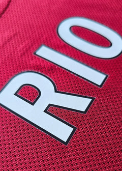 Close-up detail of red fabric featuring 'RIO' on a signed Liverpool football shirt.