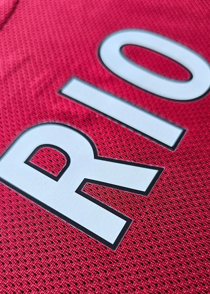 Close-up detail of red fabric featuring 'RIO' on a signed Liverpool football shirt.