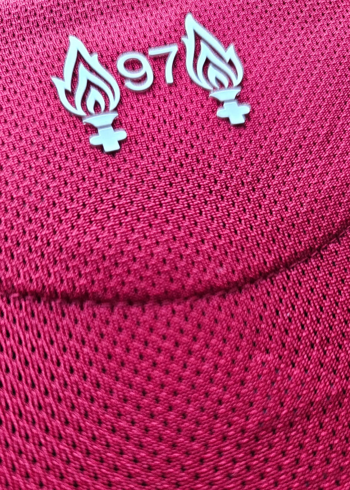Close-up of Liverpool F.C. shirt displaying the '97' emblem with flames on a red textured background.