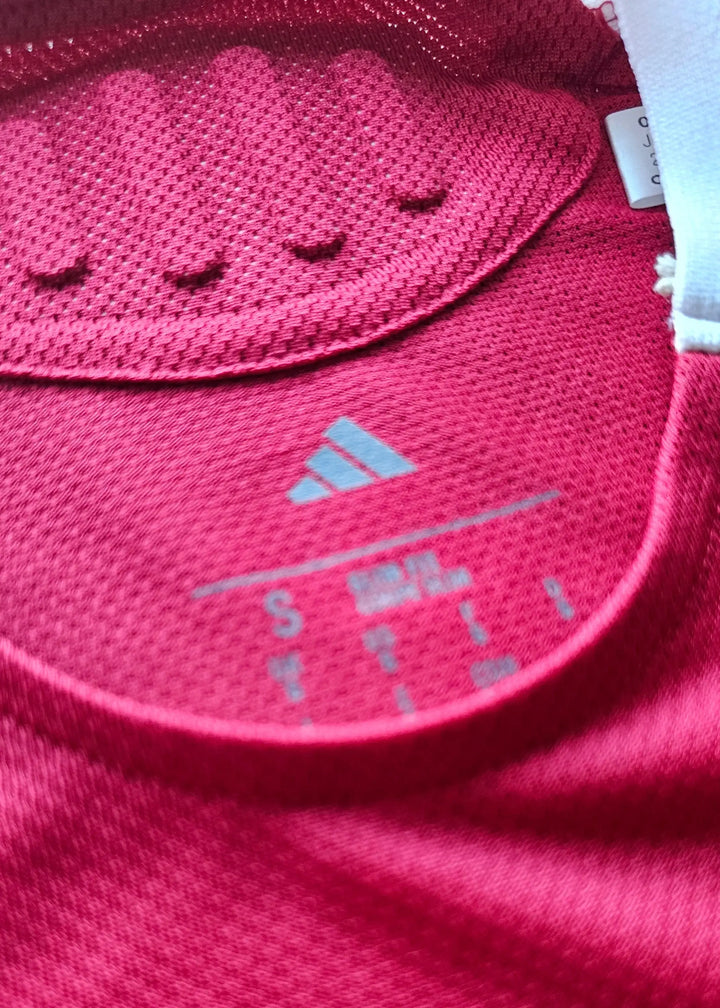 Close-up of inside neck showing adidas logo and size S label on red football shirt.