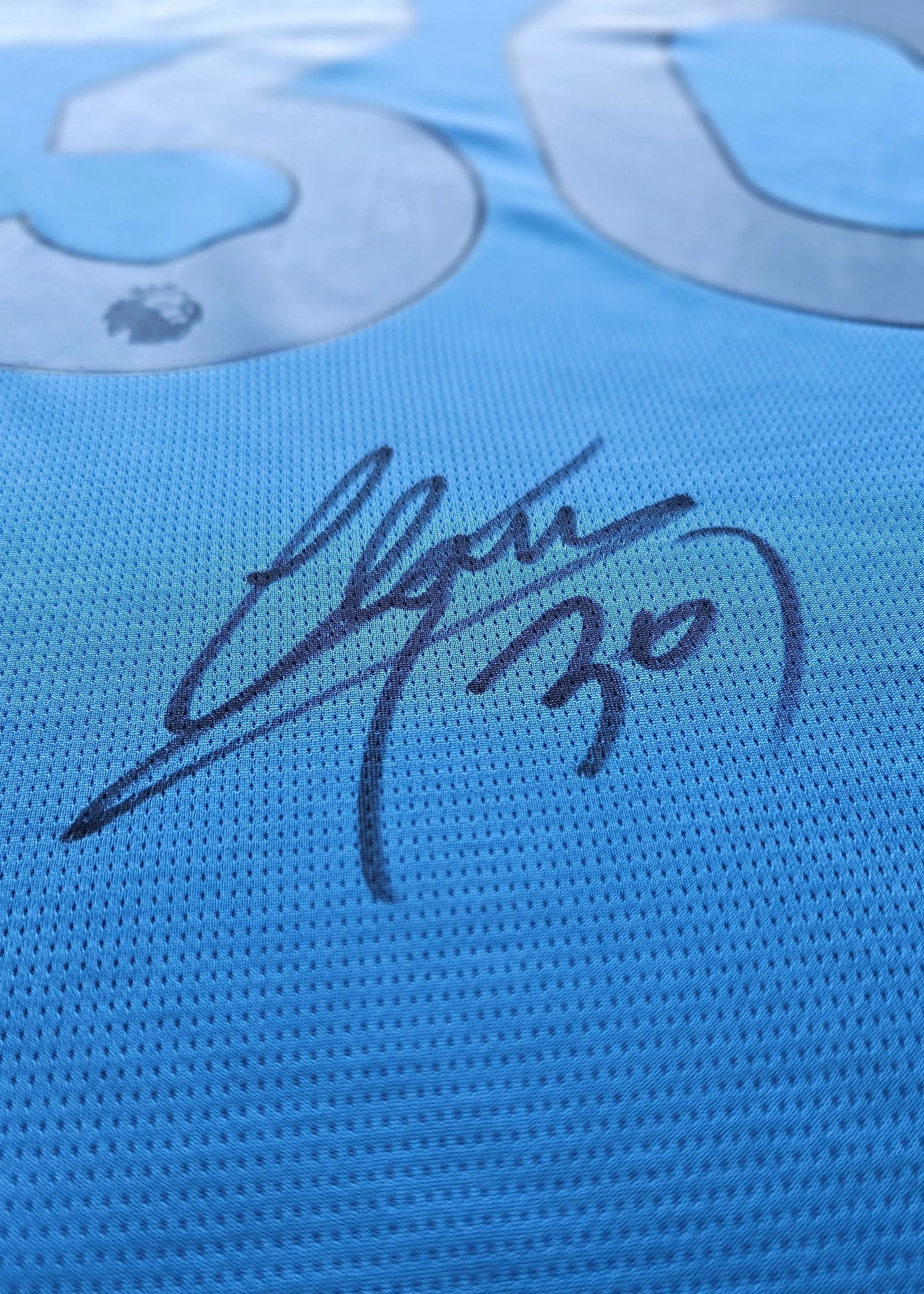Detail view showing signature and No. 30 on a blue football shirt.
