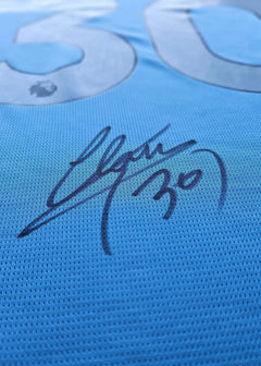 Detail view showing signature and No. 30 on a blue football shirt.