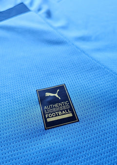 Crest detail showing the Puma logo with AUTHENTIC LICENSED FOOTBALL text on a blue background.