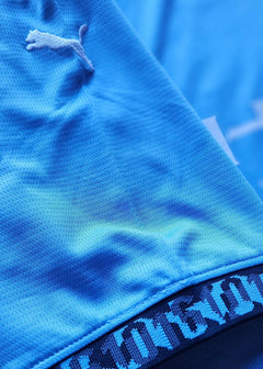 Close-up showing blue fabric with Puma logo and detail at the hem of the signed football shirt.
