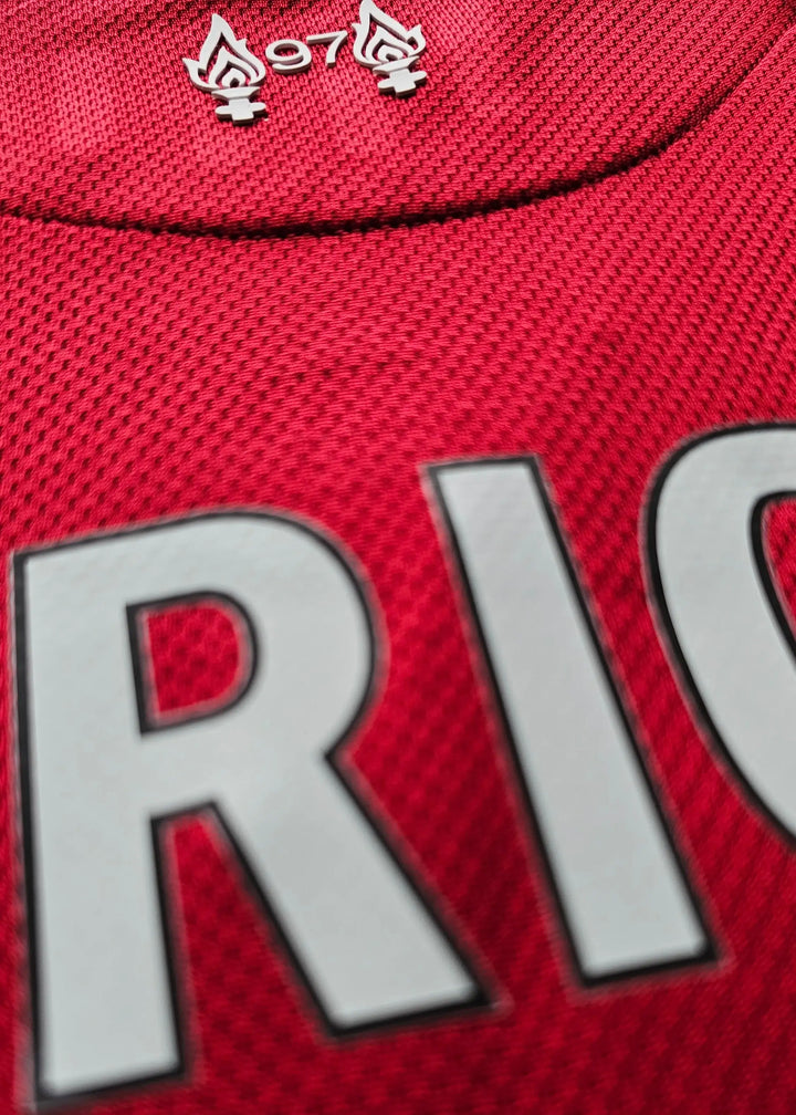 Close-up view of the name 'RIG' and '97' above flame symbols on a red football shirt.
