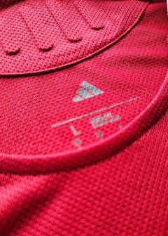 Close-up showing the adidas logo and size label "L" on a red football shirt.