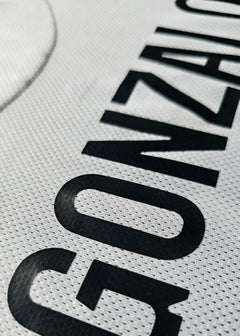 Close-up on the name 'GONZALO' in black lettering on a white shirt.