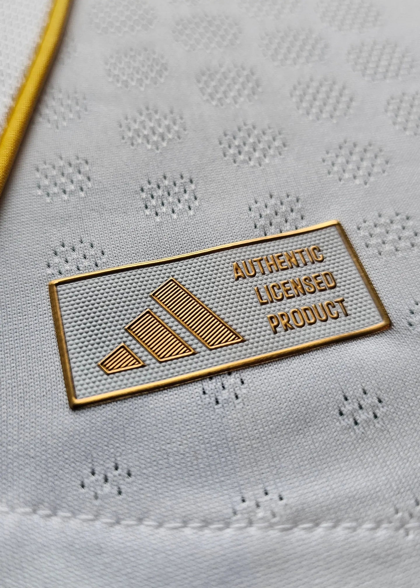 Detail showing adidas label reading 'AUTHENTIC LICENSED PRODUCT' on a textured white background.