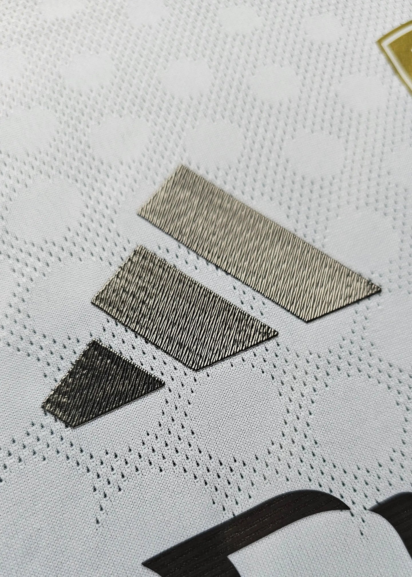 Close-up detail of fabric with textured elements and manufacturer logo in metallic stitching.