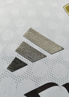 Close-up detail of fabric with textured elements and manufacturer logo in metallic stitching.