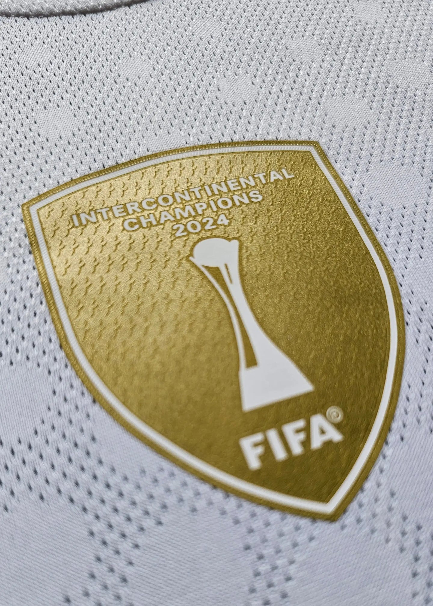 Close-up of the gold Intercontinental Champions 2024 badge with FIFA logo on white football shirt.