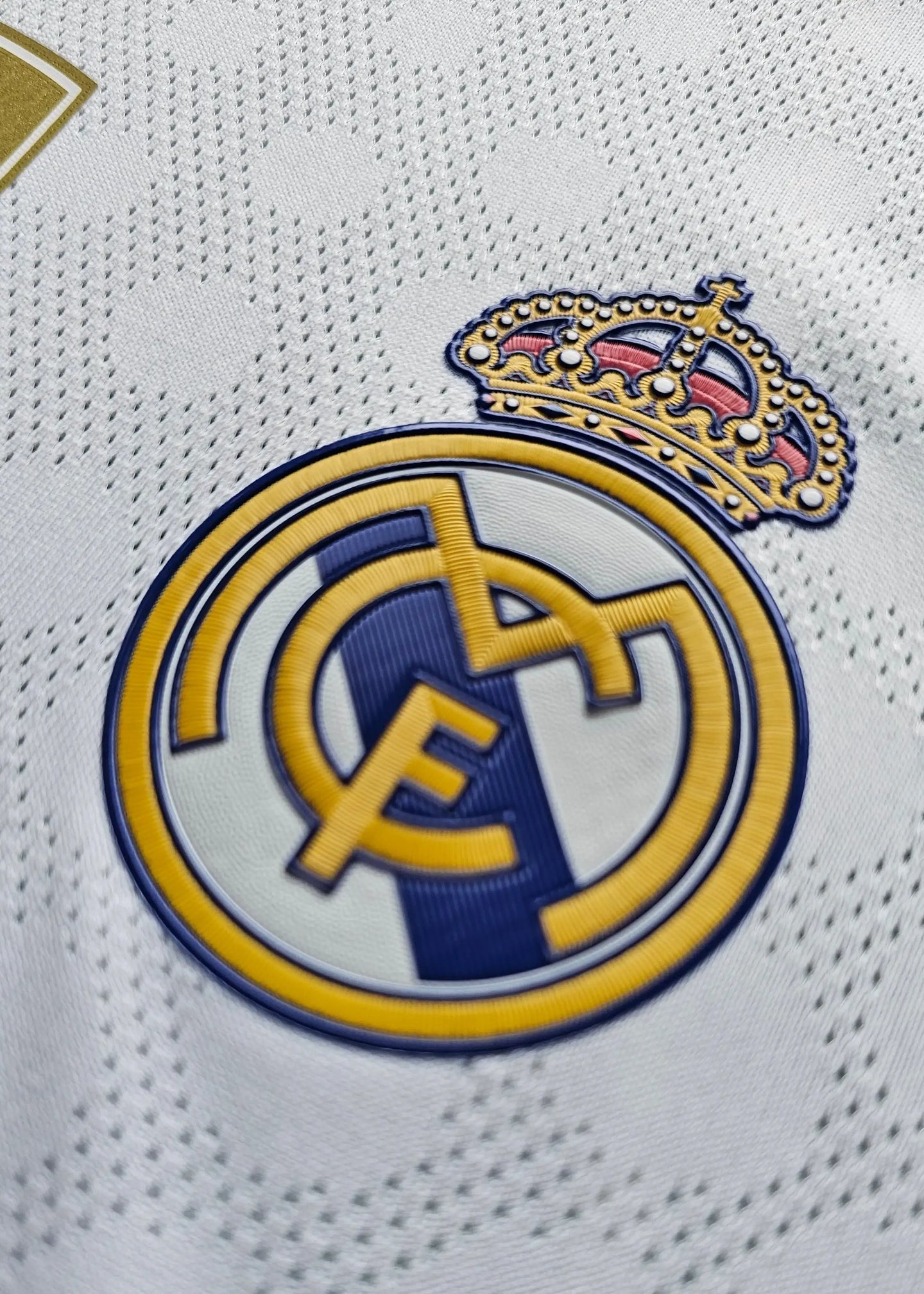 Detailed view of the Real Madrid CF crest with gold crown and blue accents.