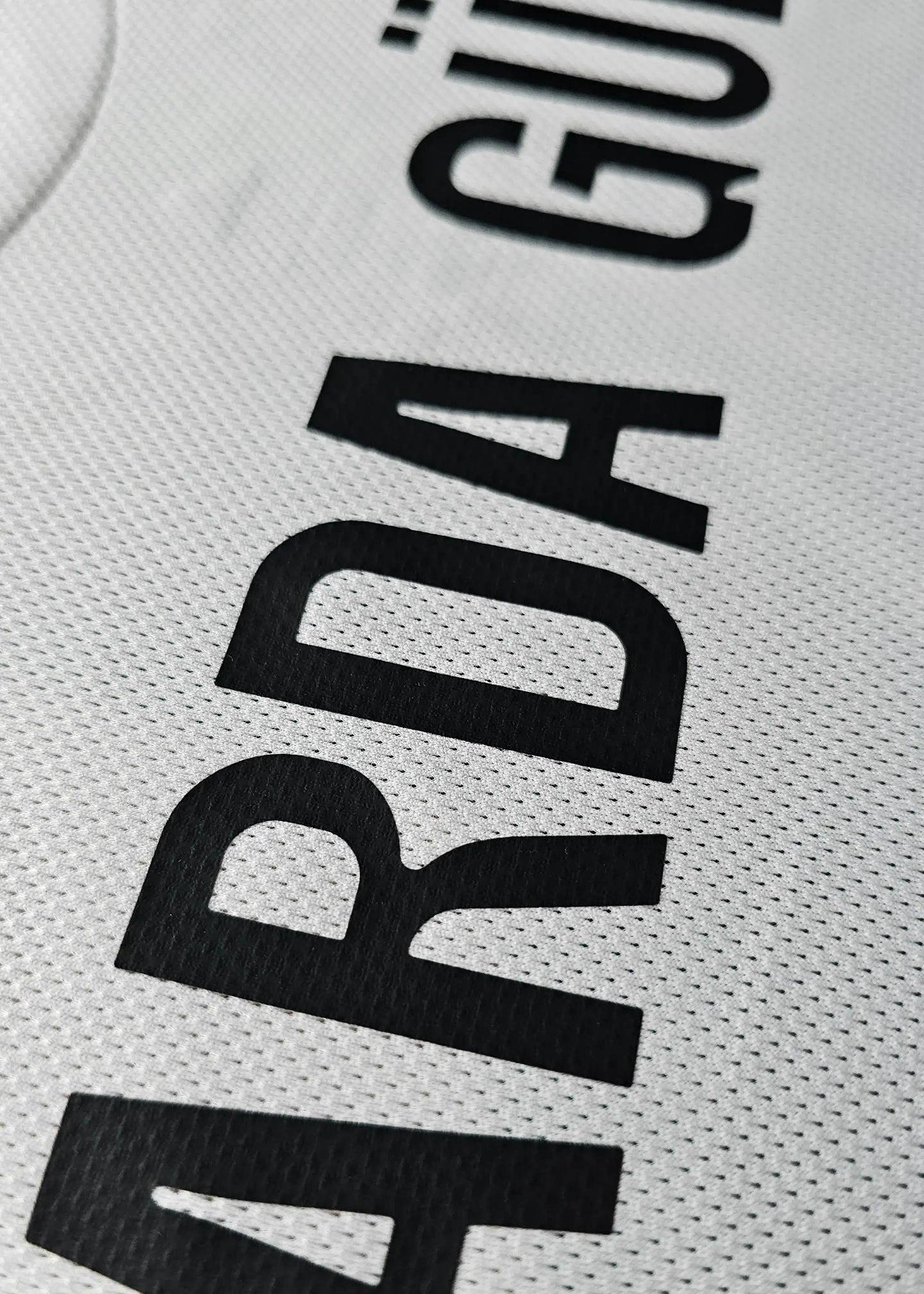Close-up detail of the name 'Güler' on a white signed football shirt.