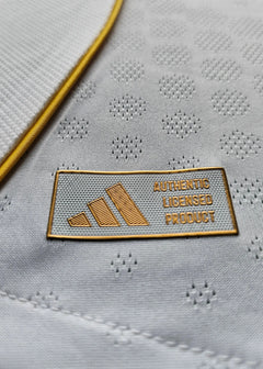 Detail displaying the adidas label reading 'AUTHENTIC LICENSED PRODUCT' on a white football shirt.