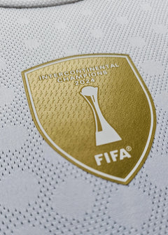 Close-up of the FIFA Intercontinental Champions 2024 badge in gold on white fabric.