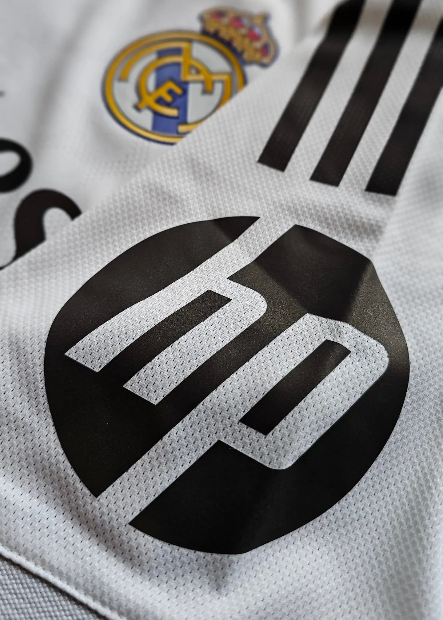 Detail of Real Madrid crest and HP logo on signed Arda Güler football shirt.