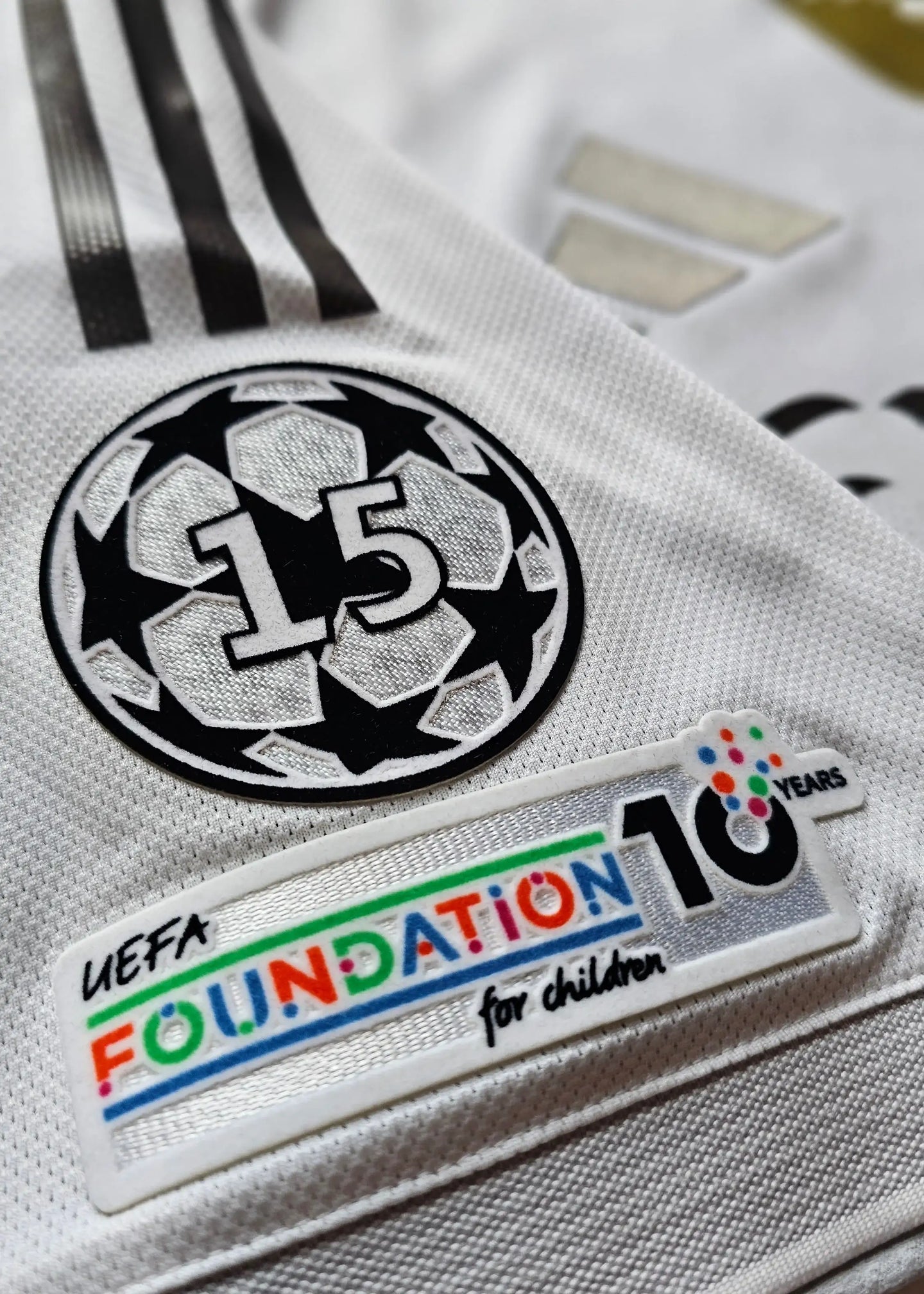 Detail showing UEFA badge with No. 15 and FOUNDATION 10 YEARS for children logo.